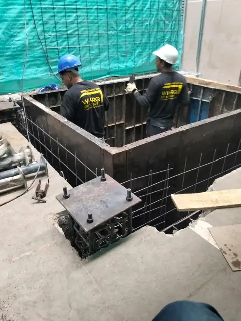 Trabajadores armando la formaleta del foso de ascensor sobre la placa de concreto