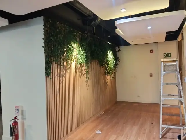 Muro verde con listones de madera y piso laminado en la remodelación de oficinas